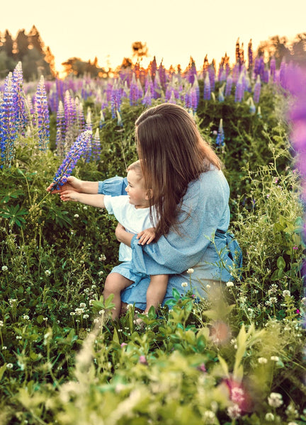 Mother and child on a field admiring nature and purple flowers.