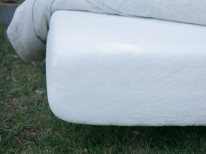 Edge of bed outdoors with Fitted White Linen Sheet