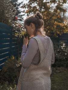 Woman in Linen Japanese Apron smelling herbs in garden
